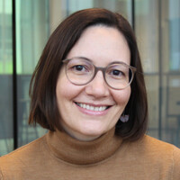 A young woman with short brown hair and glasses smiles at the camera.