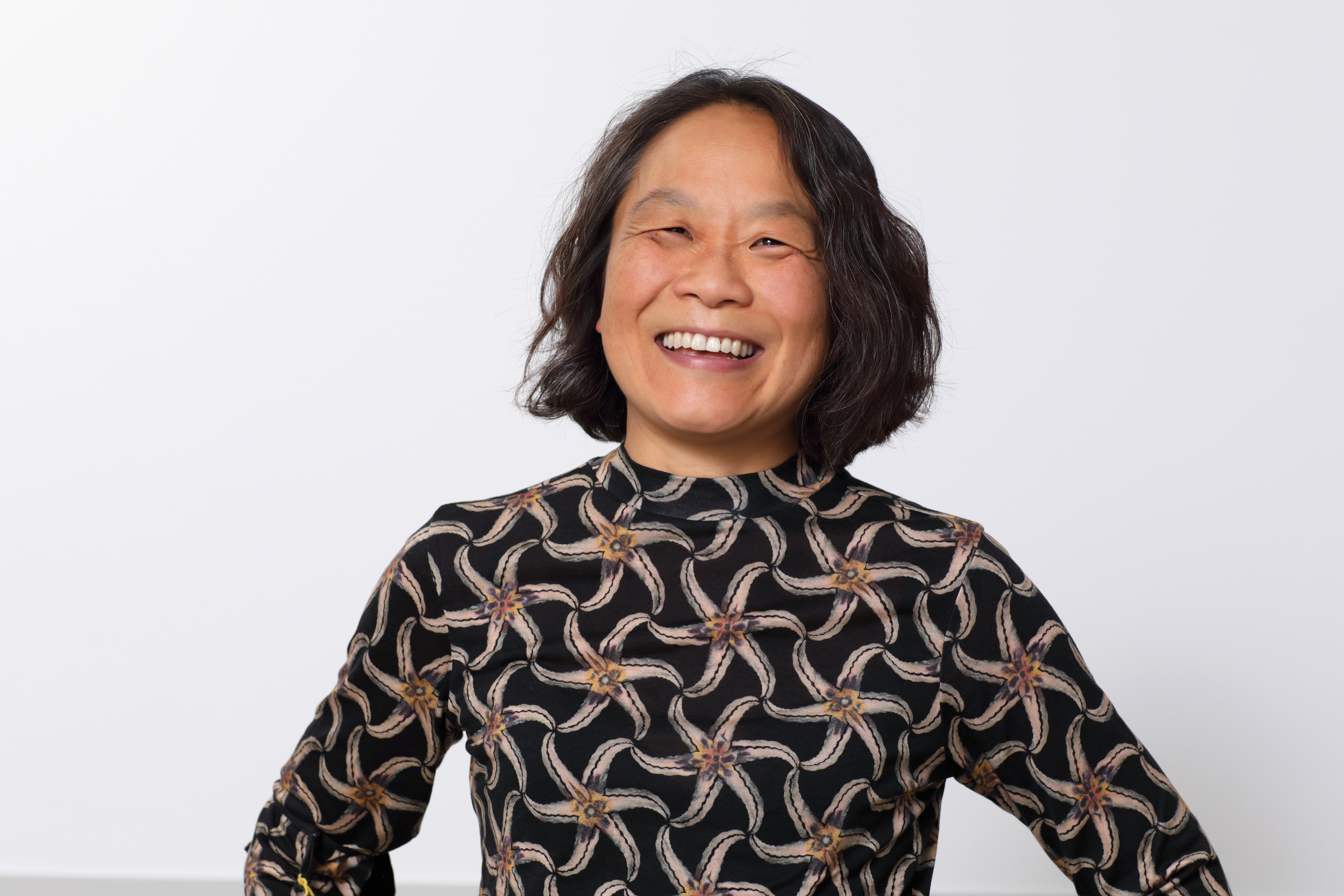 A middle-aged Asian woman smiles at the camera.